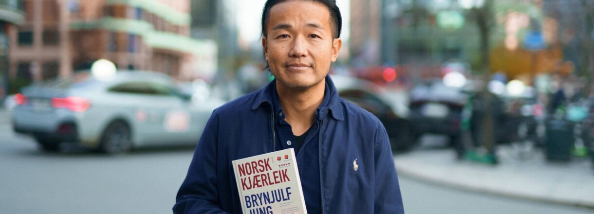 Brynjulf Jung Tjønn med boka "Norsk kjærleik" framfor uskarp bybakgrunn