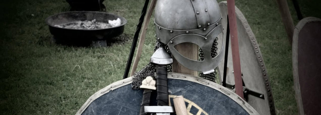 Vikinghjelm ved sidan av skjold og sverd