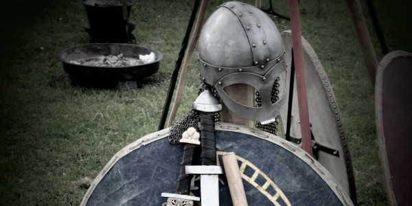 Vikinghjelm ved sidan av skjold og sverd